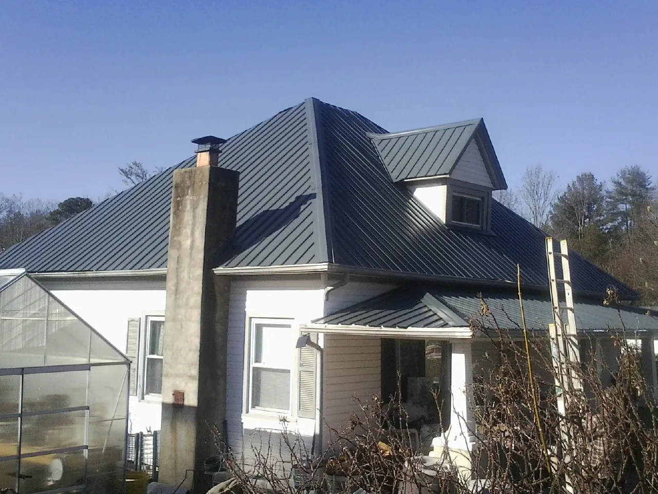 Dark blue standing seam metal roof on a white farmhouse with dormer — Slate & Tile Roof Repair by Roofing Brothers in Des Plaines