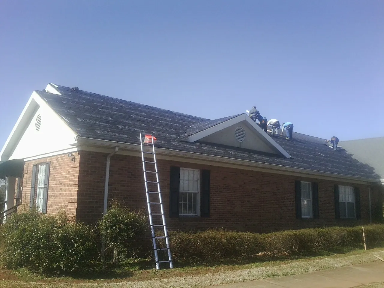Crew tearing shingles off a brick ranch roof with a ladder set — Metal Roof Repair work by our crew in Des Plaines