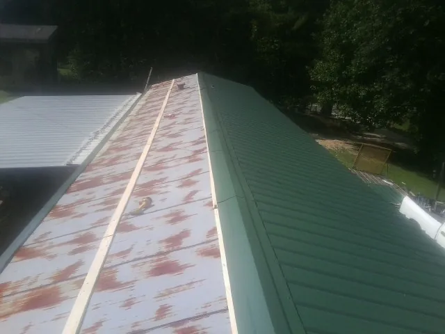 Old rusted panels beside newly installed green metal roofing — Wind Damage Roof Repair by Roofing Brothers in Des Plaines