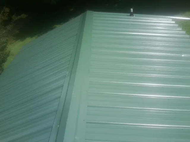 New green metal panels meeting at the ridge of a roof — Flat Roof Repair work by our crew in Des Plaines