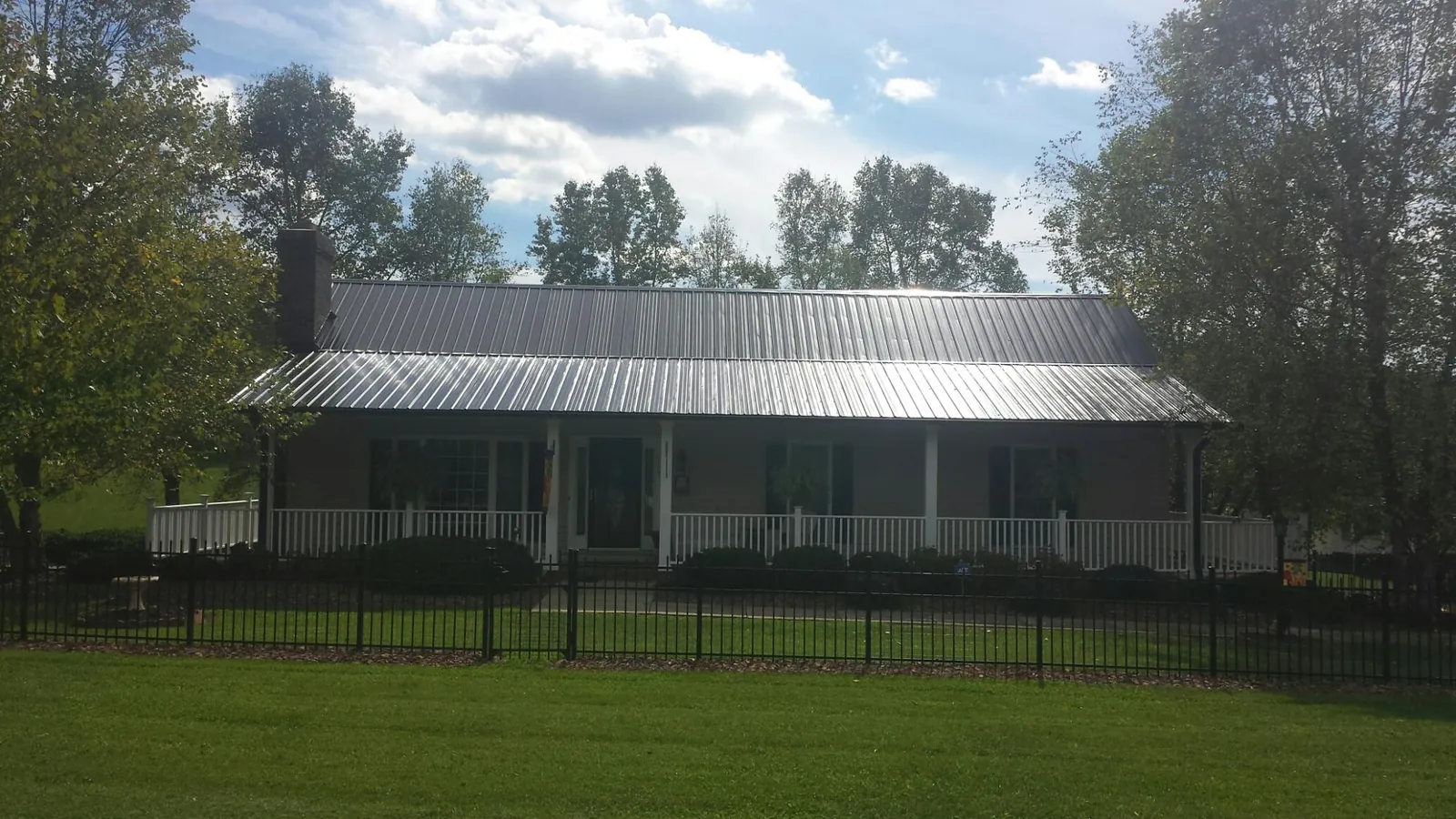 Gray metal roof on a brick ranch with a full width front porch — Gutter Guard Installation work by our crew in Des Plaines