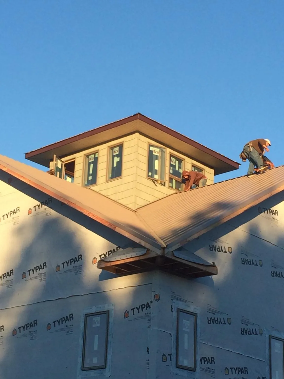 Roofers working around a rooftop cupola on a new metal roof at sunset — Roof Waterproofing in Des Plaines by Roofing Brothers